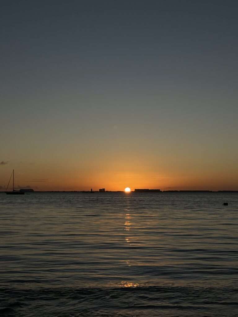 Sun setting on the horizon over calm water, Isla Mujeres