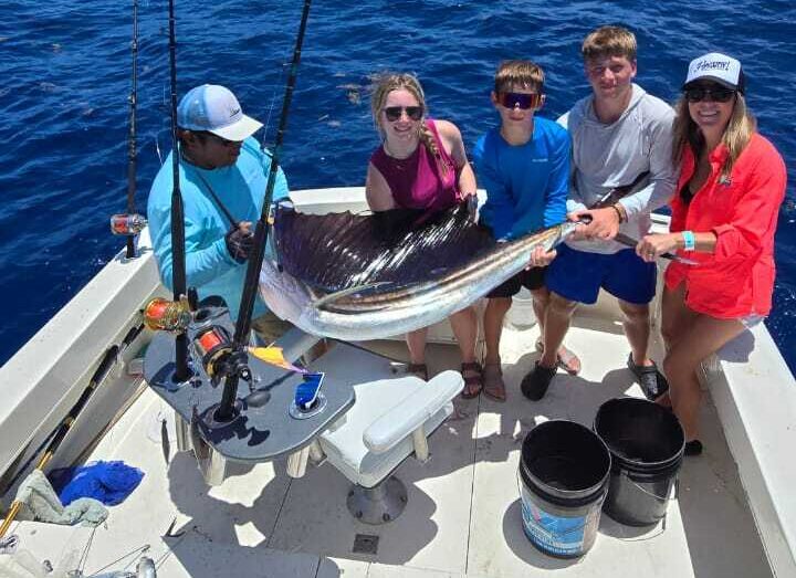 Family holding a sailfish on the Isla Sea Tours fishing boat