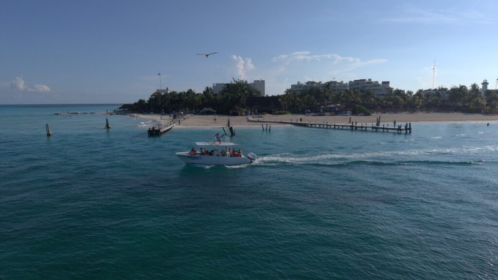 Aerial view of an Isla Sea Tours boat leaving the beach in Isla Mujeres