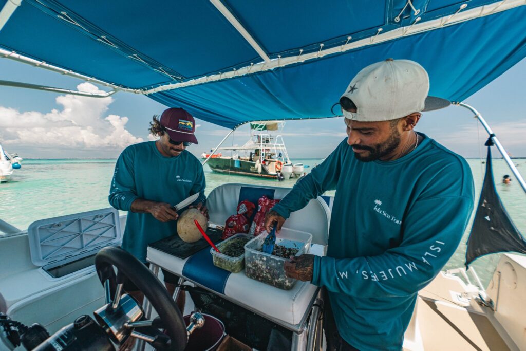 Two Isla Sea Tours guides preparing ceviche and cutting melon on board